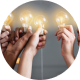 Several hands holding lit up lightbulbs